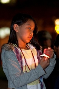 Tibetan girl holds candle during vigil for earthquake victims in Boulder, photo by Marv Ross.